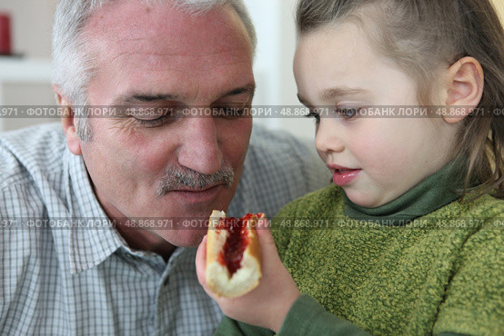 Girl feeding her grandfather bread and jam. Стоковое фото, агентство Ingram Publishing / Фотобанк Лори