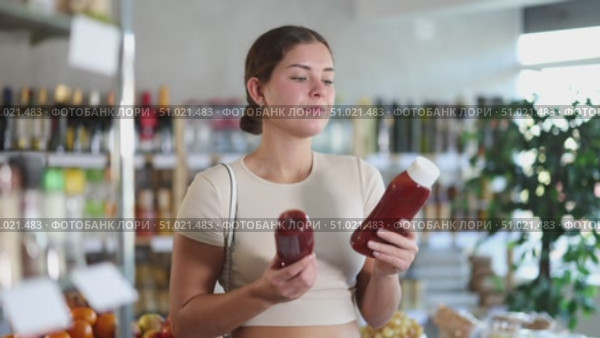 Girl hold bottle, choose and buy ketchup in store. Стоковое видео, видеограф Яков Филимонов / Фотобанк Лори