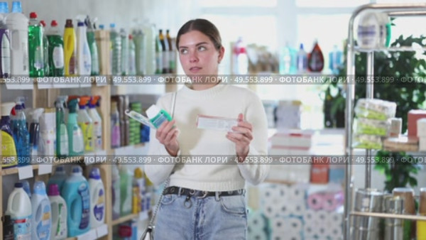 Girl housewife in household store examines package, chooses products toothpaste and related products. Стоковое видео, видеограф Яков Филимонов / Фотобанк Лори