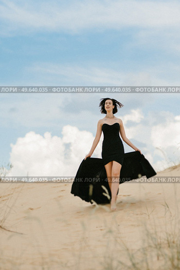 girl in a black long dress in a sandy desert under a blue sky. Стоковое фото, агентство Ingram Publishing / Фотобанк Лори