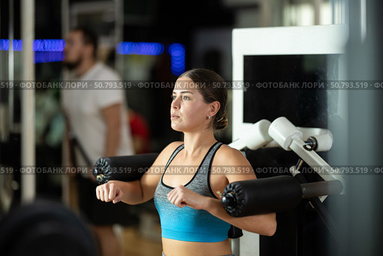 Girl in gym performs exercises for arm muscles using simulators and fitness center equipment. Стоковое фото, фотограф Яков Филимонов / Фотобанк Лори