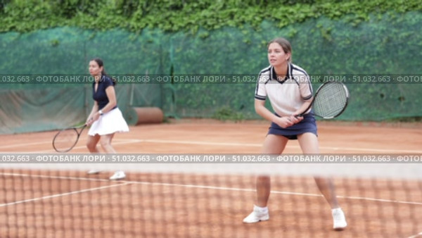 Girl plays tennis on open court with opponent. Player hits ball with racket, serves ball, and practices actively. Стоковое видео, видеограф Яков Филимонов / Фотобанк Лори