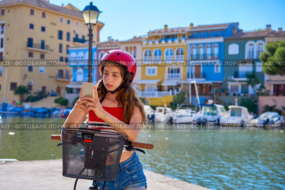 Girl riding a foldable e-bike in a Mediterranean marina port ebike. Стоковое фото, агентство Ingram Publishing / Фотобанк Лори