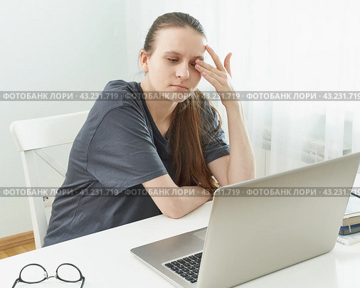 Girl rubs her eyes, her eyes are tired from strain and hurt. Concept of harmful effects of computer. Стоковое фото, фотограф Natalia Gdovskaia / Фотобанк Лори
