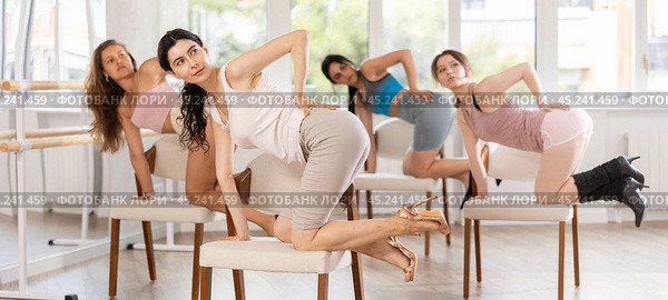 Girl sitting on knees on chair performs lap dance. Female students repeat erotic movements. Стоковое фото, фотограф Яков Филимонов / Фотобанк Лори