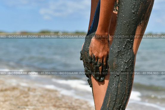 Girl smears feet with healing mud on the lake. Стоковое фото, фотограф Никита Бурденков / Фотобанк Лори