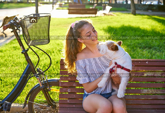 Girl with dog sitting in a park bench with turf grass background outdoor. Стоковое фото, агентство Ingram Publishing / Фотобанк Лори