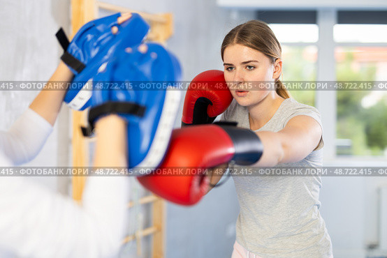 Girls works out strength and speed of boxing punch mitts with help of partner in boxing paws. Стоковое фото, фотограф Яков Филимонов / Фотобанк Лори