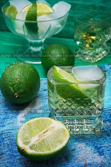 glass alcoholic drink and lime fruits on wooden texture.Selective focus. refreshing cocktail made of rum and lime with ice. Стоковое фото, агентство Ingram Publishing / Фотобанк Лори