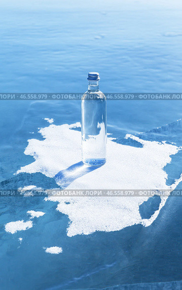 Glass bottle with cold natural drinking water stands on ice of frozen Baikal Lake on snow podium on cold winter day. Advertising and branding of drinking fresh ecological water. Nature background. Copy space. Стоковое фото, фотограф Виктория Катьянова / Фотобанк Лори