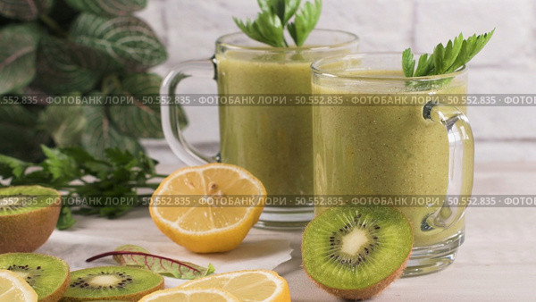 Glasses of green vegetable smoothie. Green vegetable smoothie and ingredients: Kiwi, lemon and herbs. Стоковое фото, агентство Ingram Publishing / Фотобанк Лори