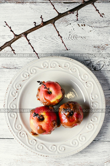 Glazed the ripe apples with branch on light background.. Sweetness from the apples in caramel. Стоковое фото, агентство Ingram Publishing / Фотобанк Лори