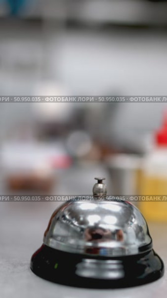 Gloved professional hand ringing service bell on stainless steel kitchen counter, signaling order completion or requesting urgent culinary assistance with metallic sound. Стоковое видео, видеограф Данил Руденко / Фотобанк Лори
