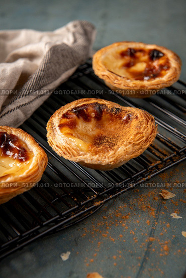 Golden-brown Portuguese custard tarts cooling on a wire rack. Стоковое фото, агентство Ingram Publishing / Фотобанк Лори