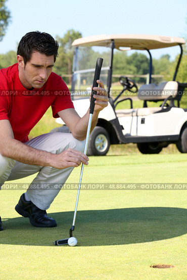Golfer crouched next to the hole. Стоковое фото, агентство Ingram Publishing / Фотобанк Лори