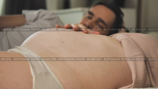 Голова мужчины на фоне беременного живота его жены. Крупный план. Будущая мать нежно поглаживает рукой округлившийся живот. Семья в ожидании чуда рождения ребенка. Стоковое видео, видеограф Воловодов Владимир / Фотобанк Лори