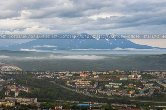 Город Петропавловск-Камчатский, Камчатский край, Дальний Восток России. Красивый городской пейзаж. Вид сверху на здания и улицы города. Вдалеке вулканы. Пасмурная погода. Низкие облака. (2022 год). Стоковое фото, фотограф Андрей Степанов / Фотобанк Лори