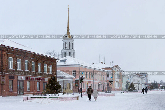 Город Шуя, Ивановская область, Россия. Зимний вид на улицу Малахия Белова в историческом центре Шуи. По заснеженной пешеходной улице гуляют люди. В старых зданиях расположены магазины. Вдали видна высокая колокольня Воскресенского собора. Популярный туристический район города. Повседневная жизнь в регионах России. Редакционное фото, фотограф Андрей Степанов / Фотобанк Лори
