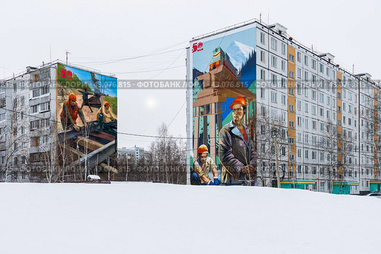 Город Тында, Амурская область, Россия. Большие граффити на стенах жилых домов, посвящённые юбилею начала строительства Байкало-Амурской магистрали (БАМ). Красивые муралы с изображениями строителей, укладывающих рельсо-шпальную решётку железнодорожных путей, и рабочих мостостроителей. (2024 год). Редакционное фото, фотограф Андрей Степанов / Фотобанк Лори