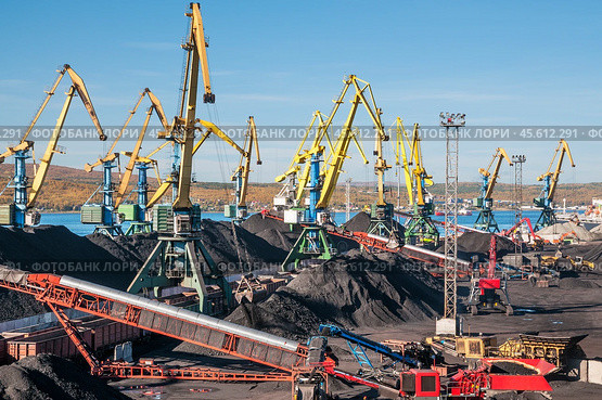 Горы угля в морском порту, грузовые вагоны из под угля, телескопические ленточные транспортеры, которые перераспределяют уголь по участку. Стоковое фото, фотограф Павел Просянов / Фотобанк Лори