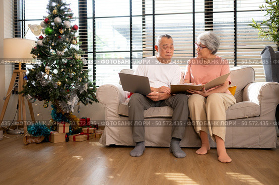 Grandfather and grandmother are reviewing the expenses and the food menu to host their children and grandchildren during the Christmas holiday at home. Стоковое фото, агентство Ingram Publishing / Фотобанк Лори