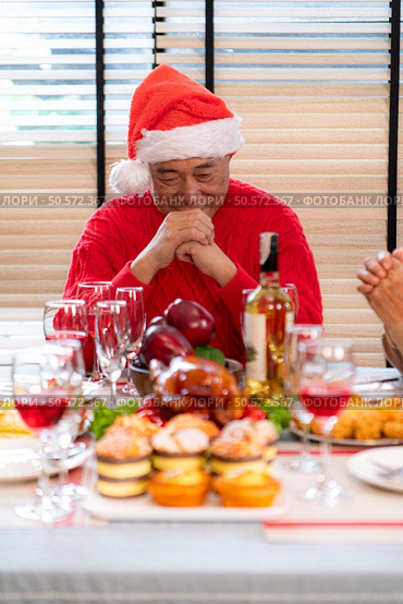 Grandfather leads a prayer and blessing before the family meal during the Christmas celebration at home. Стоковое фото, агентство Ingram Publishing / Фотобанк Лори