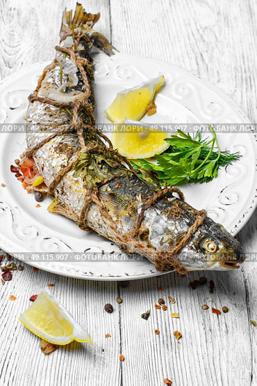 grill fish on light plate. whole carcass of fish grilled on light plate on light background. Стоковое фото, агентство Ingram Publishing / Фотобанк Лори