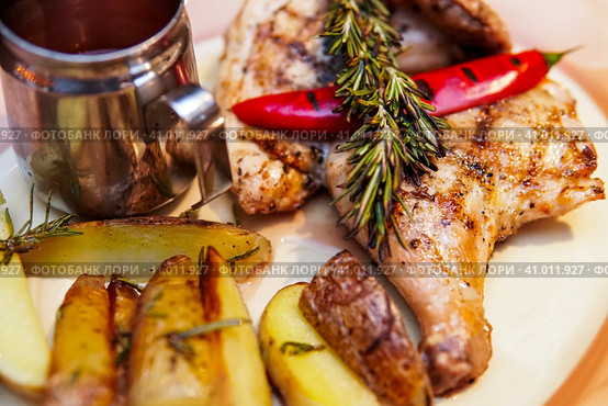 Grilled chicken, baked with potatoes and chili pepper. Food is served on a platter with tomato sauce and decorated with rosemary branch. Курица-гриль, запеченная с картофелем и перцем чили. Блюдо подается на блюде с томатным соусом и украшается веточкой розмарина. Стоковое фото, фотограф Дмитрий Березнев / Фотобанк Лори