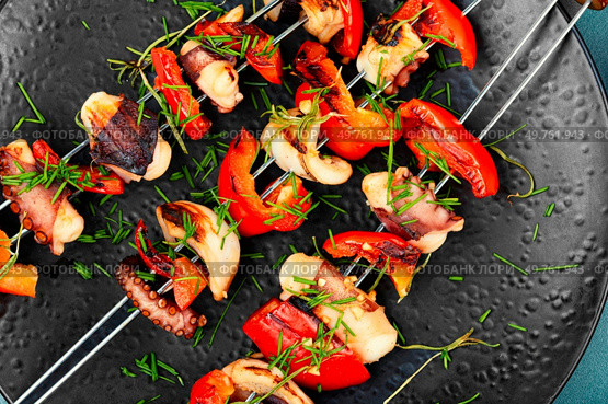 Grilled octopus skewers garnished with bell pepper. Seafood. Close up.. A plate of octopus skewers. Стоковое фото, агентство Ingram Publishing / Фотобанк Лори