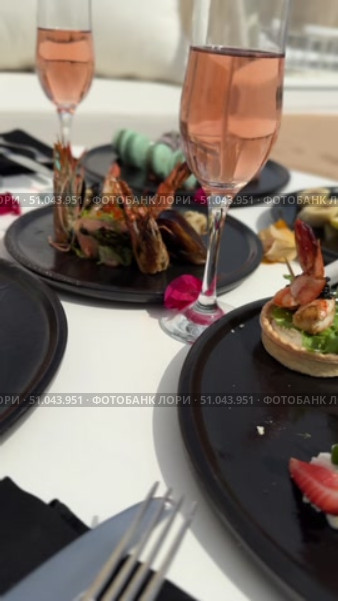 Grilled salmon steak with crispy skin sauteed vegetables and lemon served in outdoor restaurant in summer light A wooden table with a variety of dishes containing seafood, vegetables and fruit.Hand holding a spoon ready to eat pineapple fried rice with shrimp, served in a pineapple bowl, surrounded by fresh fruits and tea on a cozy table setting.Party Sea Food platter with salmon and prawns, low angle view, close-up Sea food party platter, extreme Whole poached salmon with cucumber slices for scales, high end party platter, overhead view Tiger prawns on the grill Macarooni cookies floating on blue background, levitation, macarooni cookies, dessert, sweets, colorful, delicious Two Glasses of Pink Champagne with Macarons and Oranges Elegant seaside celebration with seafood, pink floral decor, and sparkling wine overlooking the ocean. Стоковое видео, видеограф Zita Khasanova / Фотобанк Лори