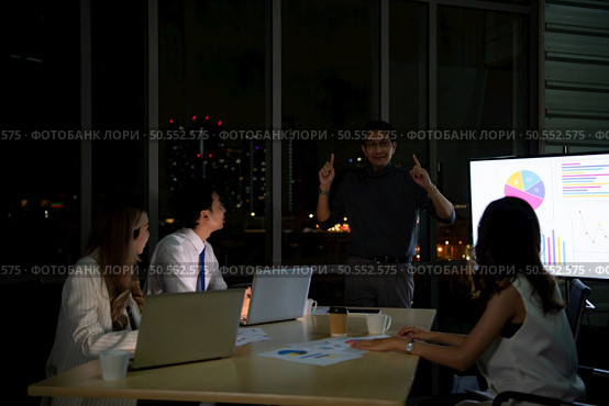 Group of broker international stock traders working actively at night in office, Everyone is congratulating the team on their success. Стоковое фото, агентство Ingram Publishing / Фотобанк Лори