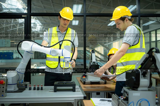 Group of engineers and technicians learning the technology to control hand robots for industrial usage. Стоковое фото, агентство Ingram Publishing / Фотобанк Лори
