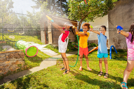 Group of kids play fun wet game with water pistols. Стоковое фото, фотограф Сергей Новиков / Фотобанк Лори