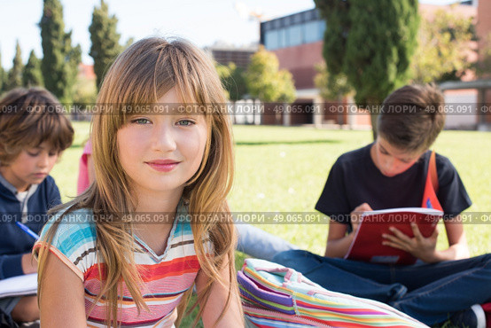 Group of little students sitting on the grass at school. Стоковое фото, агентство Ingram Publishing / Фотобанк Лори
