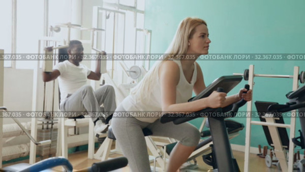 Group of people exercising with weight and on simulators in gym. Стоковое видео, видеограф Яков Филимонов / Фотобанк Лори