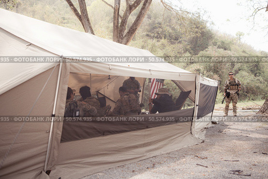 Group of soldiers in camouflage uniforms hold weapons in a field tent, Plan and prepare for combat training. Стоковое фото, агентство Ingram Publishing / Фотобанк Лори