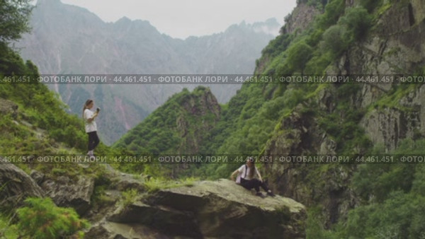 Group of tourists, while hiking in the mountains, decided to arrange a photo shoot on a large rock. Slow motion. Стоковое видео, видеограф Strunov David / Фотобанк Лори