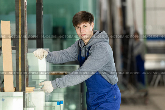 Guy glazer employee in blue overall works in glass processing shop. Стоковое фото, фотограф Яков Филимонов / Фотобанк Лори