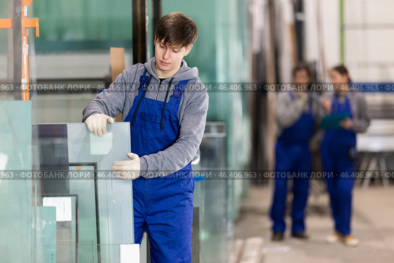Guy glazer employee in blue overall works in glass processing shop. Стоковое фото, фотограф Яков Филимонов / Фотобанк Лори