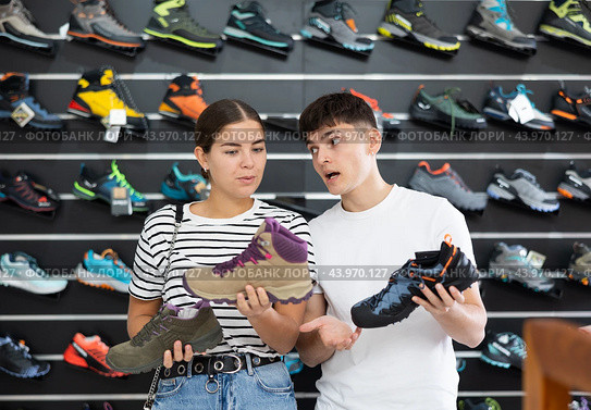 Guy with girlfriend, view specialized shoes in store, near showcase with summer trecking cross-shoes. Стоковое фото, фотограф Яков Филимонов / Фотобанк Лори