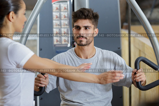 gym trainer showing right position to use gym machine. Стоковое фото, агентство Ingram Publishing / Фотобанк Лори