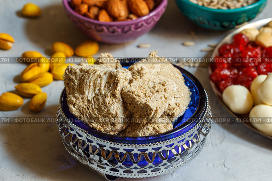 Halva in a blue glass bowl with patterns and other oriental sweets and nuts on a gray countertop. Close-up. Стоковое фото, фотограф Bogdanova Mariia / Фотобанк Лори