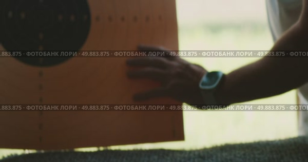 Hand holding paper target sheet at shooting range, man sets shooting target outdoor. Стоковое видео, видеограф Igor Tichonow / Фотобанк Лори