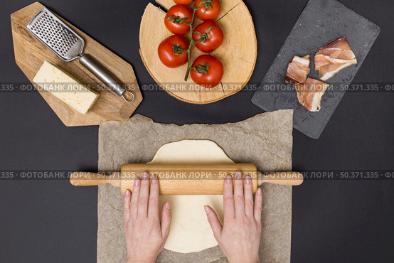 hand rolling pizza dough parchment paper with pizza ingredient black background. Стоковое фото, агентство Ingram Publishing / Фотобанк Лори