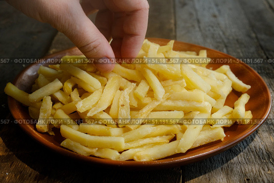 Hand takes golden french fries from plate. Стоковое фото, фотограф Маргарита Кирьякова / Фотобанк Лори