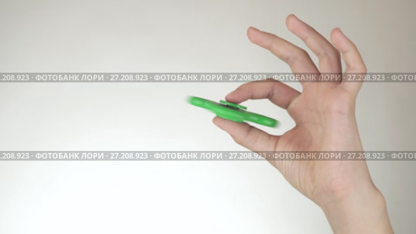 Hands of a teenage girl spin a green fidget spinner on white background stock footage video. Стоковое видео, видеограф Юлия Машкова / Фотобанк Лори