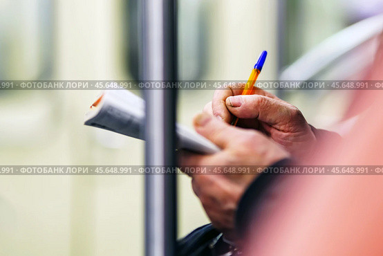 Hands of an old man write in the magazine of crosswords in the subway. Стоковое фото, фотограф Татьяна Степанищева / Фотобанк Лори