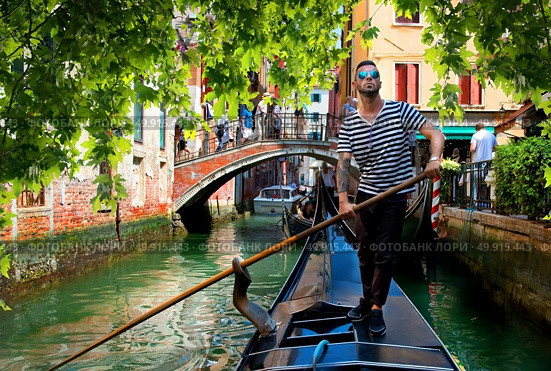 Handsome gondolier during gondola ride on the street of Venice, Italy. Gondolier in Venice. Стоковое фото, агентство Ingram Publishing / Фотобанк Лори
