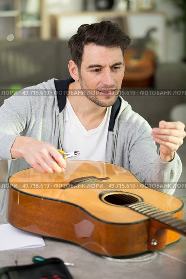 handsome man repairing guitar at workshop. Стоковое фото, агентство Ingram Publishing / Фотобанк Лори