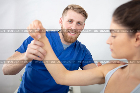 handsome physiotherapist treating patients shoulder. Стоковое фото, агентство Ingram Publishing / Фотобанк Лори